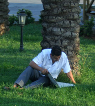 читающий под пальмой газету мужчина